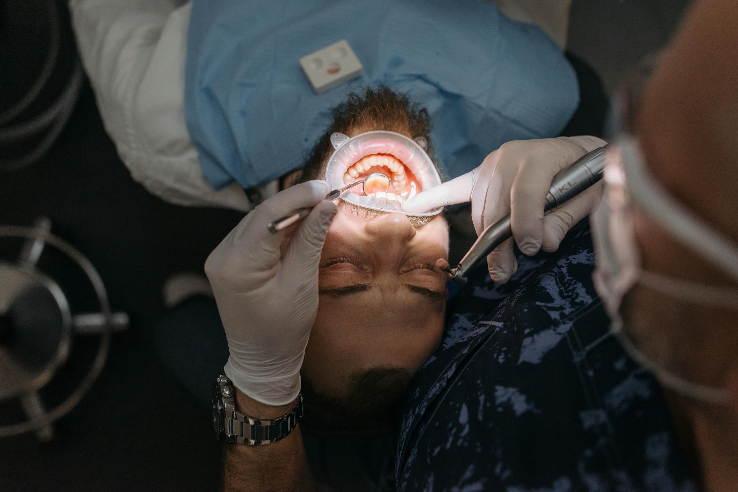 A dentist performing a thorough dental examination on an adult male patient in a clinic.